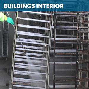 Worker power washing racks inside a commercial building